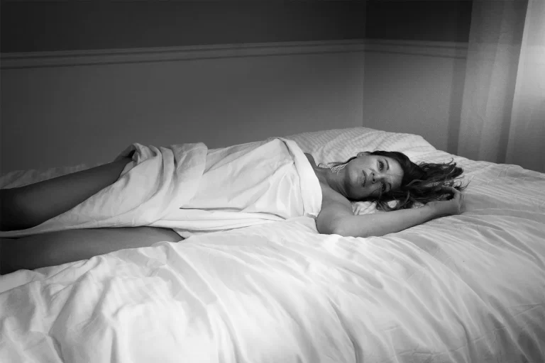 A relaxed woman under sheets on the bed