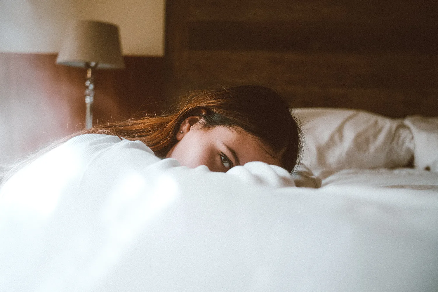 A woman's head lying on the bed, looking at the camera